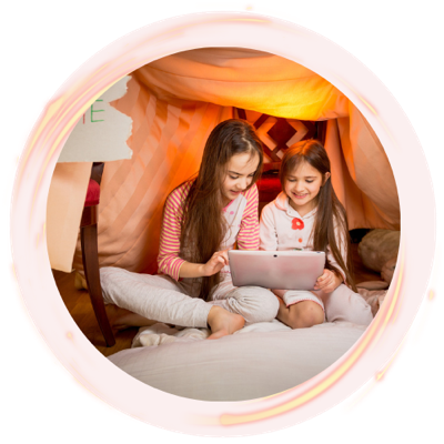 Twee meisjes kijken samen op een tablet in een dekenfort