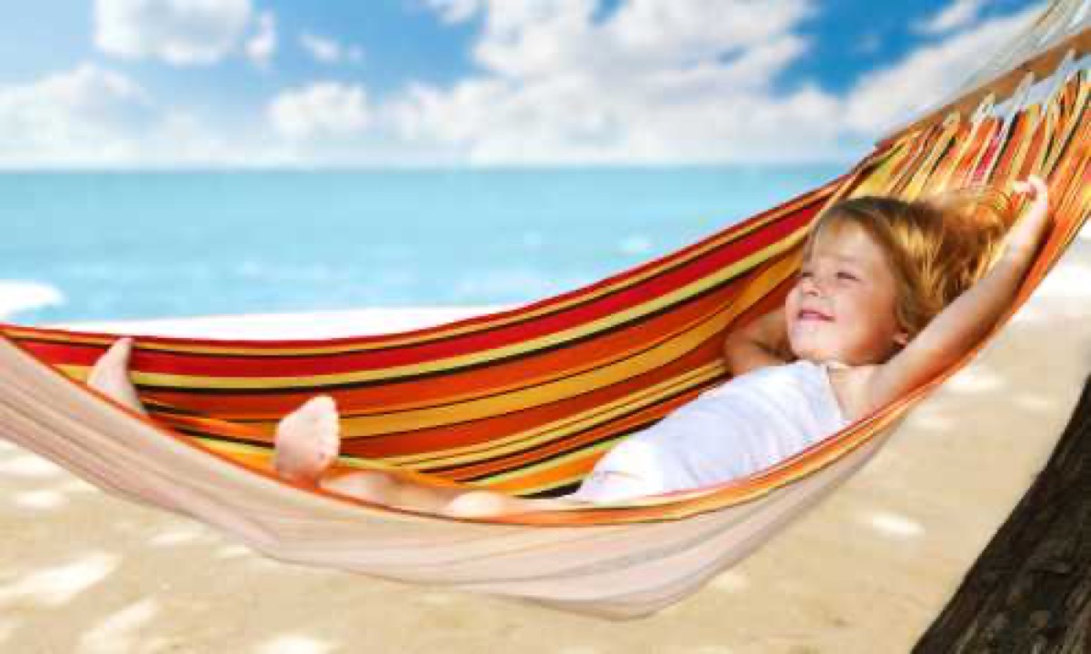 Meisje ligt ontspannen lachend in een hangmat aan het strand